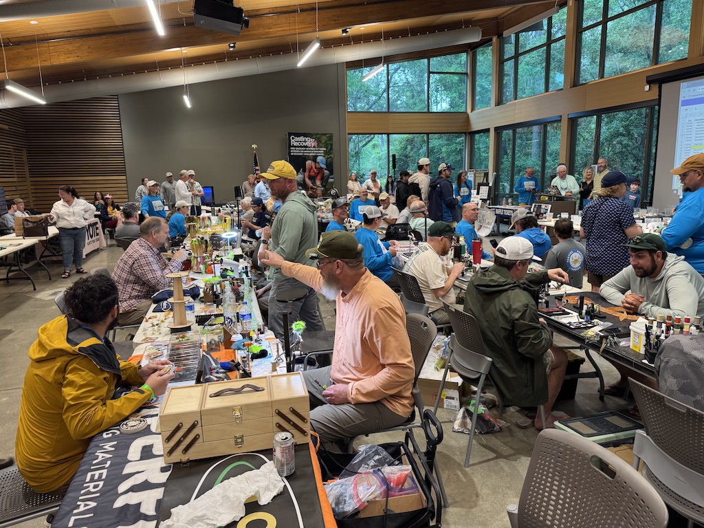 A view of a busy fishing event, with people buying and selling lures and other angling gear