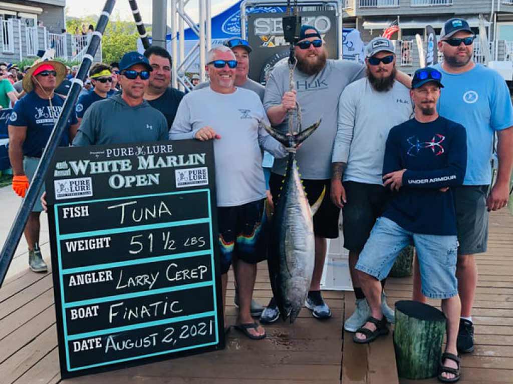 A group of men pose on a dock at the White Marlin Open with a big Tuna, caught by Finatic, as shown on the sign 