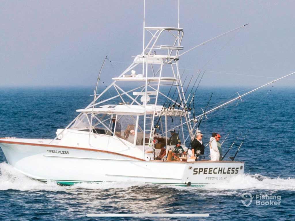 A white sportfishing boat called “Speechless” with several people onboard’s moving across open water near Manteo, NC, equipped with multiple fishing rods.