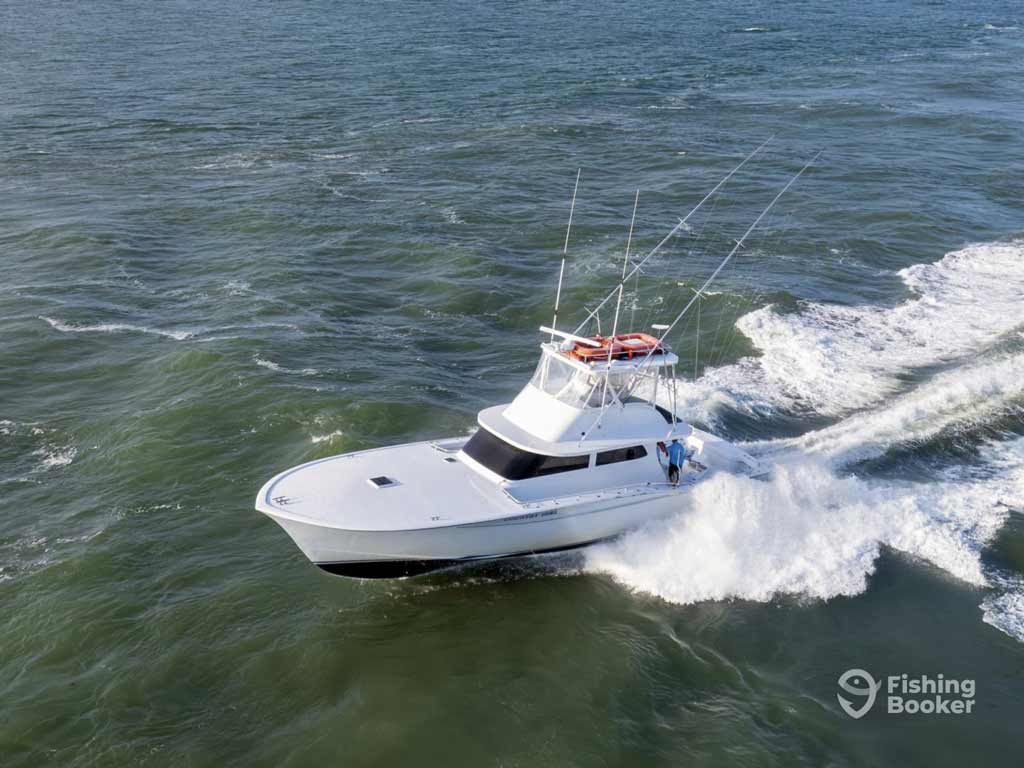 A white sportfishing boat with rod holders speeds across choppy water heading offshore for the Pirate’s Cove Billfish Tournament fishing competition
